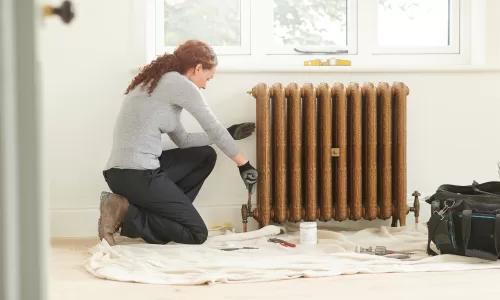 female plumber installing cast iron radiator